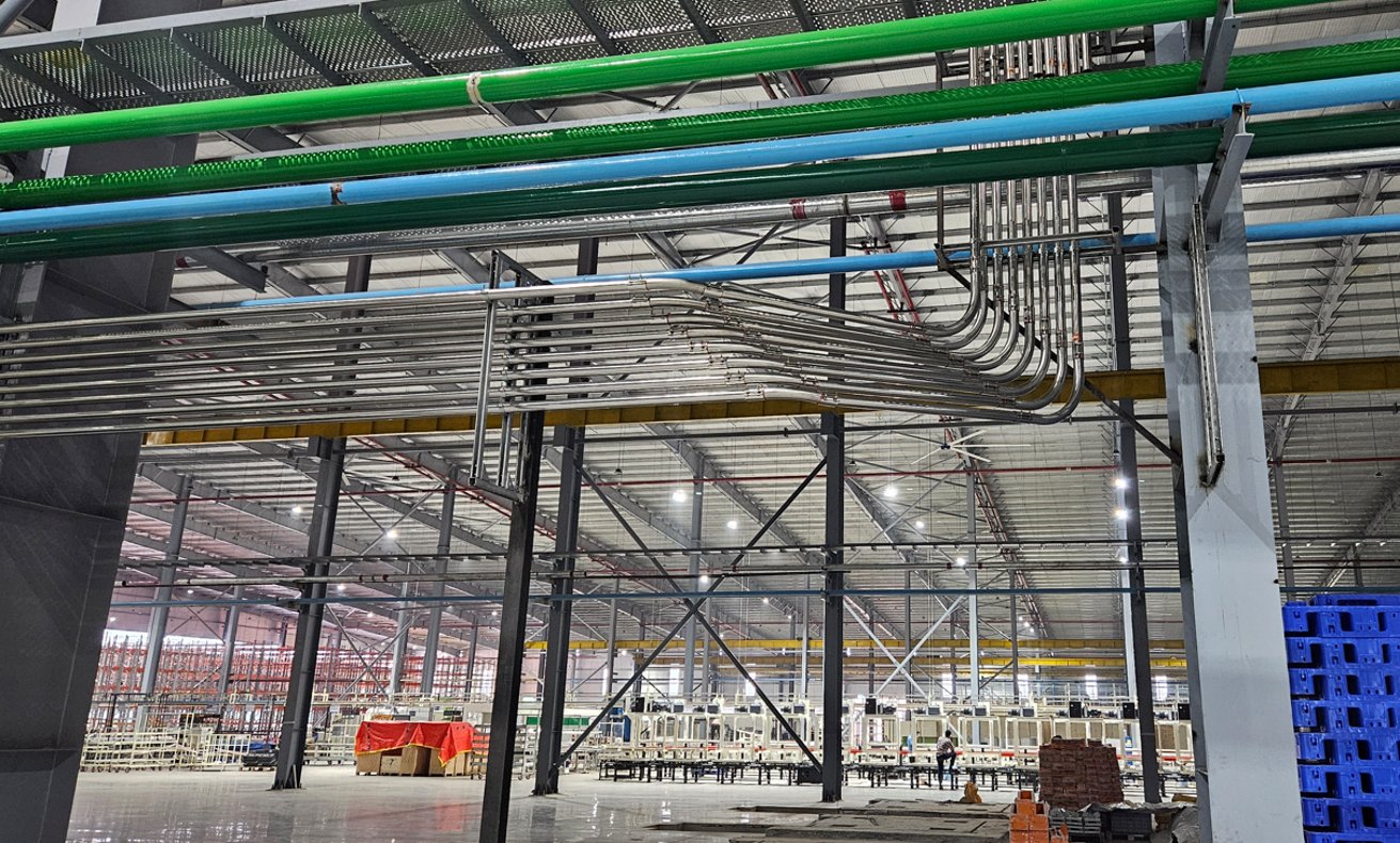 Material-conveying pipes and electrical conduits routed through a production hall